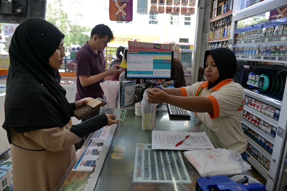 A cashier, right, takes payment for a customer’s goods at a supermarket in Kuala Lumpur on April 1, 2015. (AFP Photo/Mohd Rasfan)




