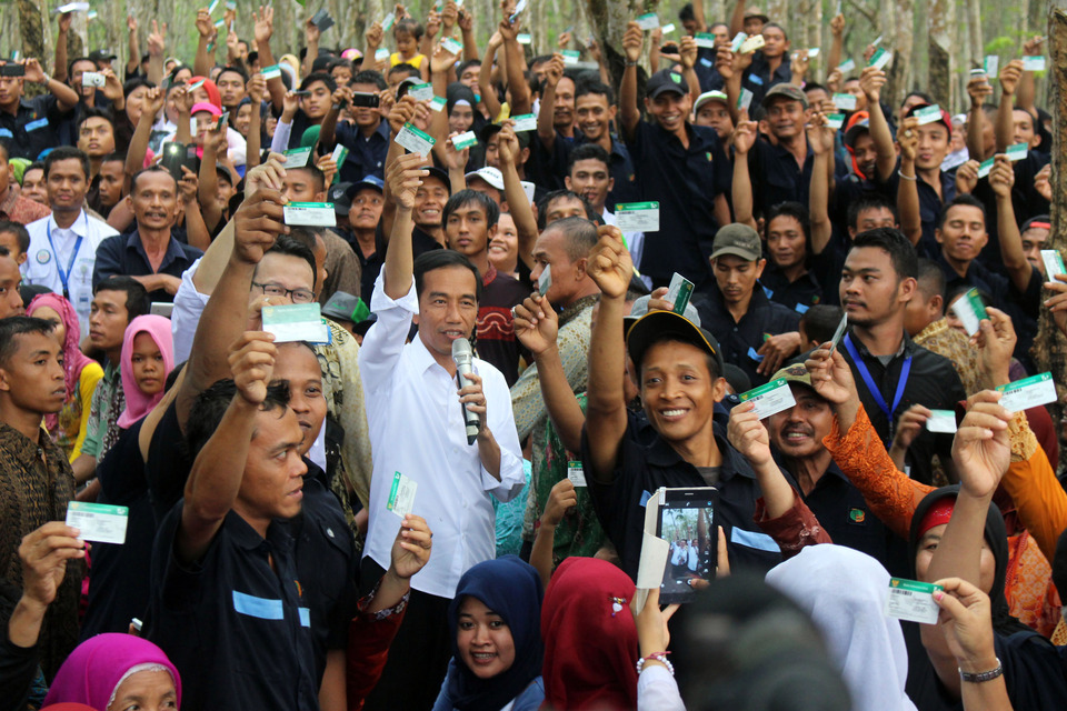 President Joko Widodo, center, distributes the Indonesia Health Card (KIS) to workers at a rubber plantation in North Sumatra. (Antara Foto/Septianda Perdana)