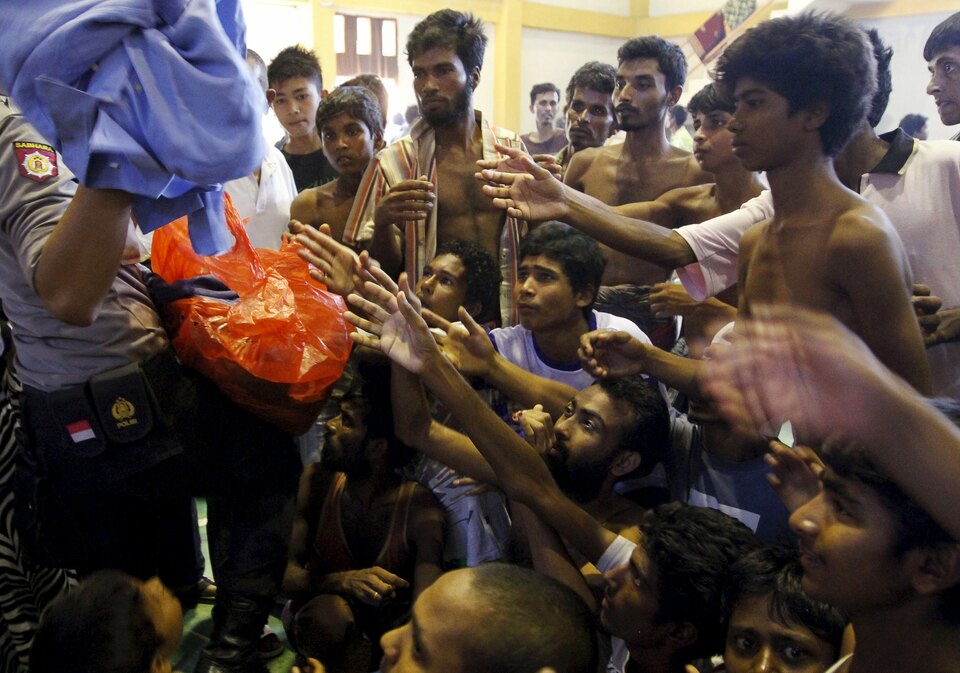 An Indonesian policeman distributes used clothes to migrants believed to be Rohingya inside a shelter in Lhoksukon, Aceh, in May 2015. (Reuters Photo/Roni Bintang)