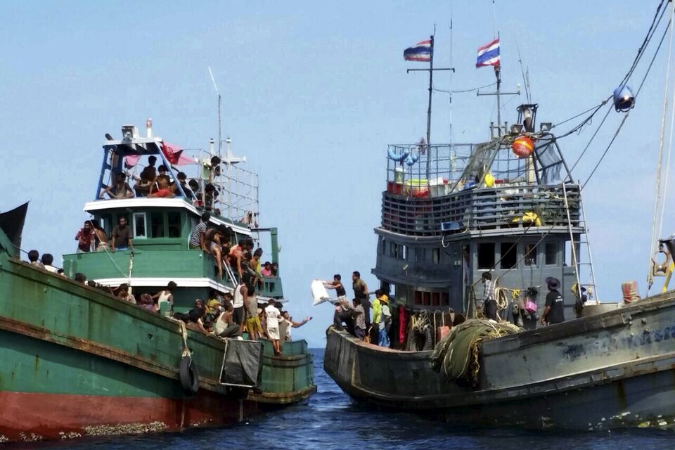 Thai fishermen, right, give some supplies to migrants on a boat drifting 17 kilometers off the coast of the southern island of Koh Lipe on Thursday. (Reuters Photo)