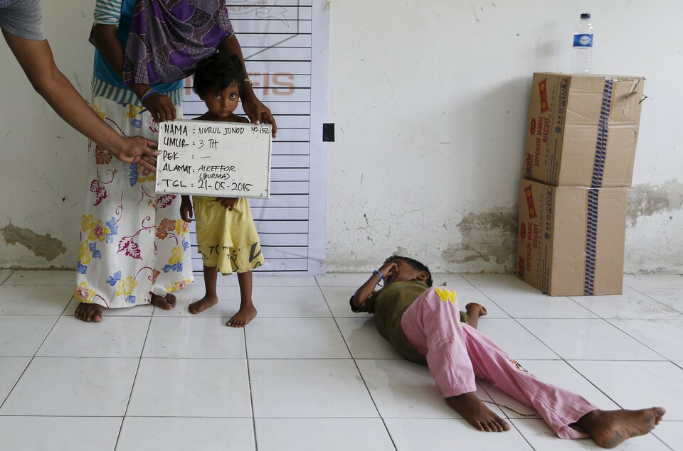 An Indonesian immigration officer helps to hold a placard for a Rohingya migrant child, who recently arrived in East Aceh district by boat, getting a picture taken for identification purposes inside a temporary compound for refugees on Thursday. A general from Myanmar, where the Rohingya live under apartheid-like conditions, claims some of the ‘boatpeople’ are only pretending to be Rohingya in order to get UN assistance. (Reuters Photo/Beawiharta)