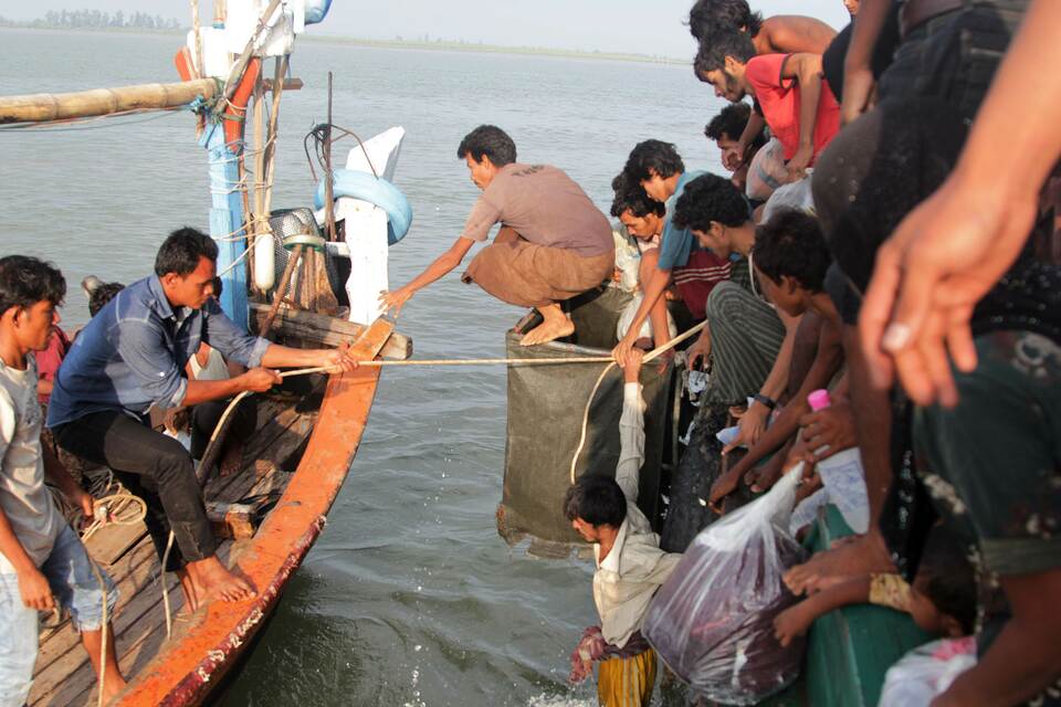Acehnese fishermen, left, help transfer Rohingya migrants, right, from their boat off the coast near the city of Geulumpang in Indonesia's East Aceh district of Aceh province on May 20, 2015. (AFP Photo/Januar)
