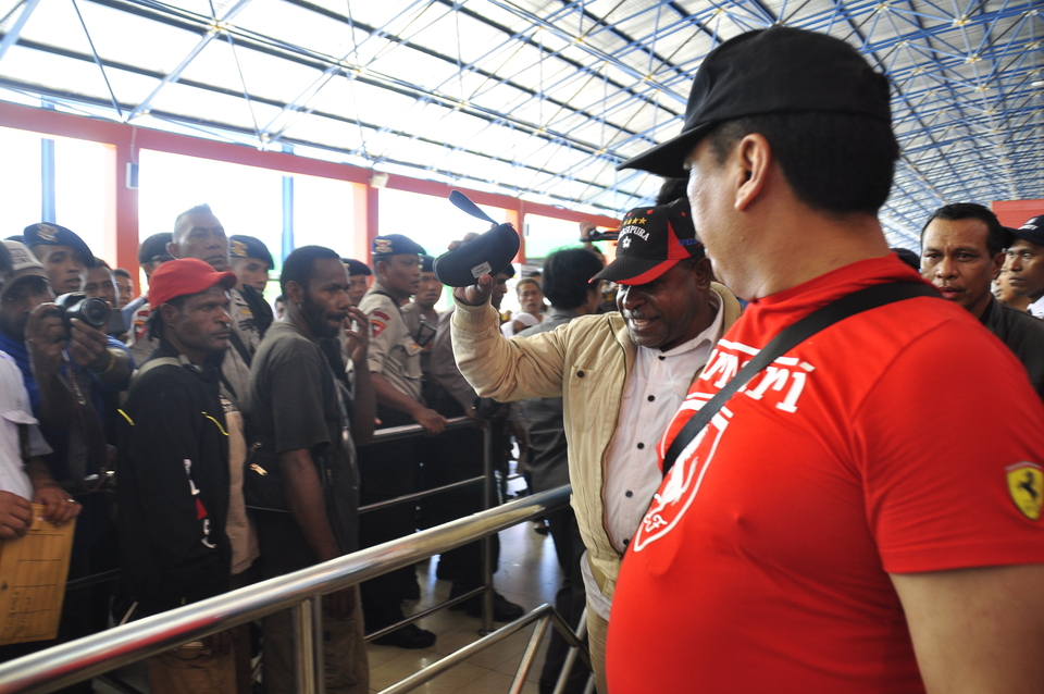 Sarmi District Head Mesak Manibor, with red and black cap, at Jayapura's Sentani Airport on Thursday, on his way to a Jakarta detention facility. (Antara Photo/Alfian Rumagit)