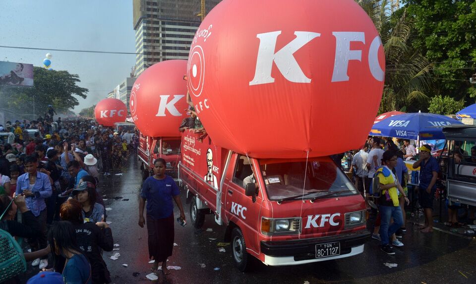 This photo taken on April 14, 2015 shows KFC advertising cars seen during Myanmar's water festival in Yangon. The Thilawa Special Economic Zone outside Yangon is expected to bring some 100 factories employing 50,000 people, according to Reuters. (AFP Photo/Phyo Hein Kyaw)