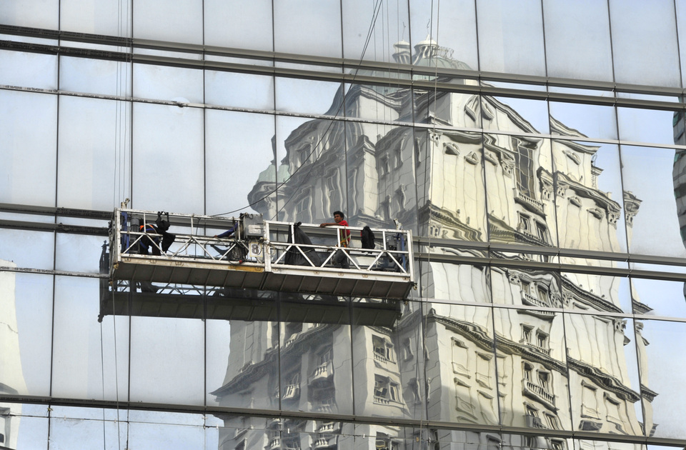 Workers clean the windows of an office building in Jakarta. (Antara Photo/Andika Wahyu)