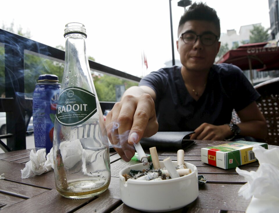 Zhang Wei, an office worker who has been a smoker for the last five years, smokes at an outdoor cafe in Beijing, China, June 1, 2015. China's capital city was sprinkled with red-uniformed volunteers, propaganda banners and no-smoking signs on Monday as Beijing unrolled ambitious new curbs on a popular habit. Zhang told Reuters that the restrictions on smoking will help his plan to stop smoking. (Reuters Photo/Kim Kyung-hoon)