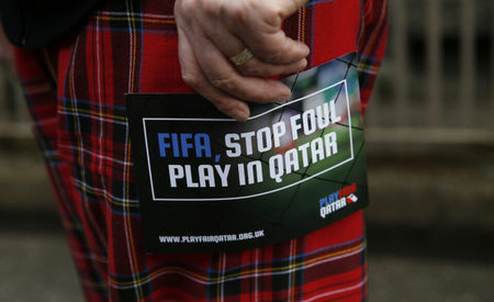 A demonstrator holds a flyer protesting Qatar's treatment of workers building stadiums for the 2022 World Cup. (Reuters Photo/Russell Cheyne)