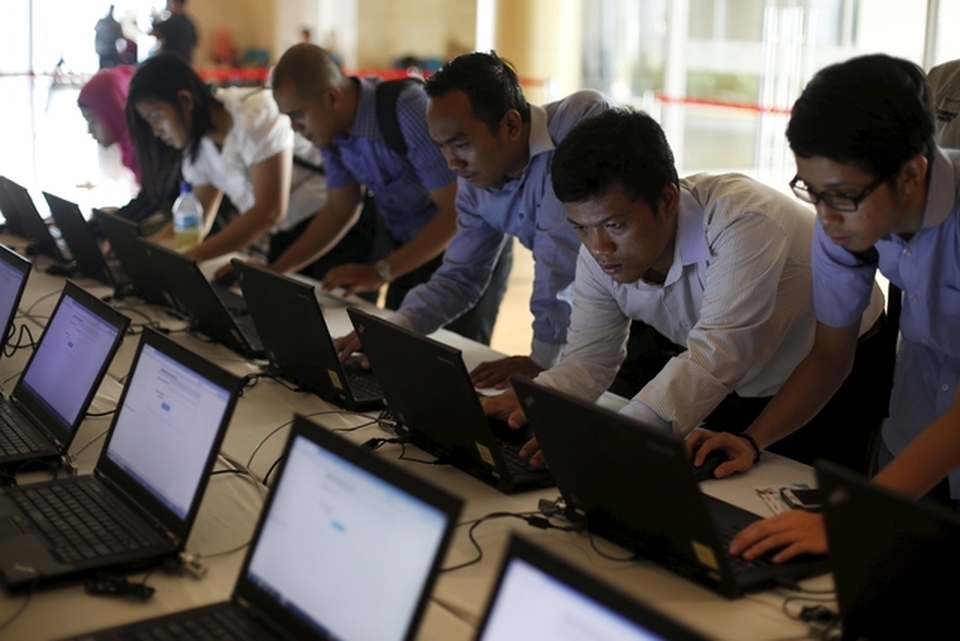 Indonesian youths fill out job application forms on laptops provided by organizers at the Indonesia Techno Career job fair in Jakarta, on June 11. (Reuters Photo/Beawiharta)