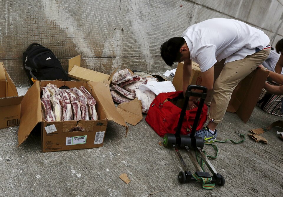 A man unpacks boxes of frozen beef ribs from the United States on a side street in an industrial area in Hong Kong on Monday. The meat will be hand-carried and smuggled across the border into mainland China to circumvent import restrictions. (Reuters Photo/Bobby Yip)