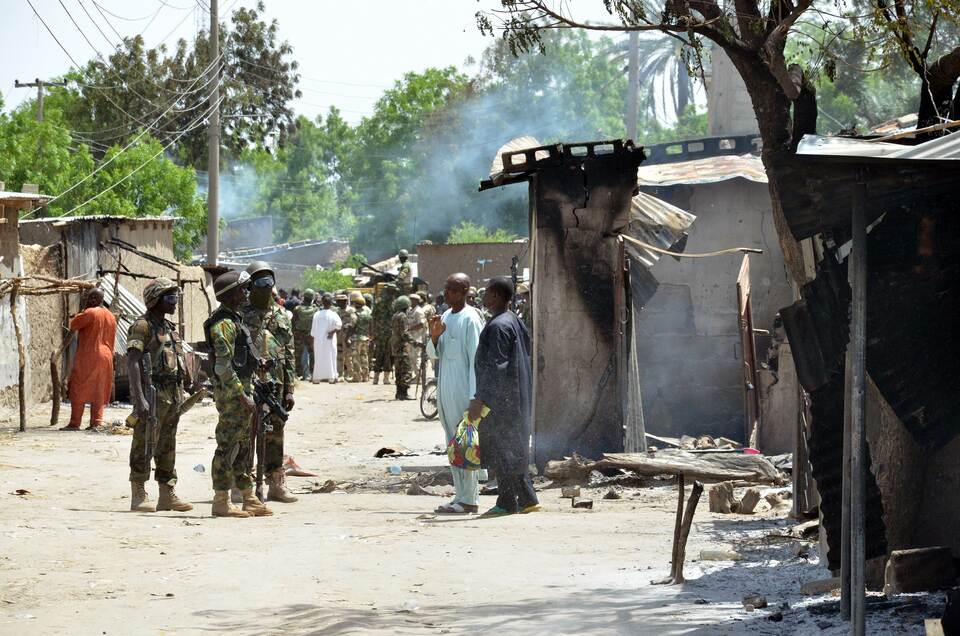 Soldiers speak to people standing away from houses burnt by Boko Haram Islamists at Zabarmari, a fishing and farming village near Maiduguri, northeast Nigeria, on July 3. (AFP Photo)