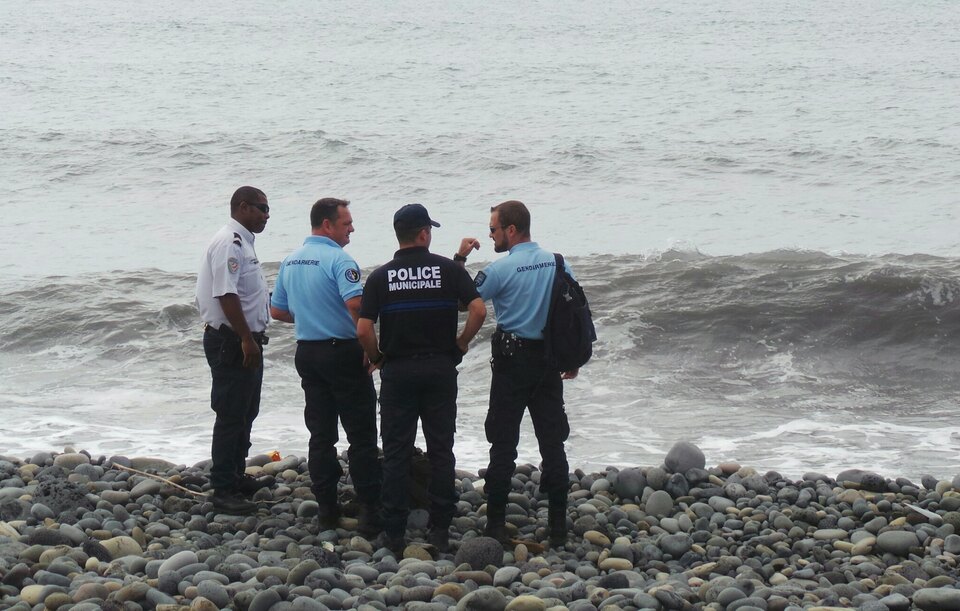 French gendarmes and police stand on the beach where a large piece of plane debris was found in Saint-Andre, on the French Indian Ocean island of La Réunion, on July 29. France’s BEA air crash investigation agency said it was examining the debris, in coordination with Malaysian and Australian authorities, to determine whether it came from Malaysia Airlines Flight MH370, which vanished last year in one of the biggest mysteries in aviation history. (Reuters Photo/Zinfos974/Prisca Bigot)
