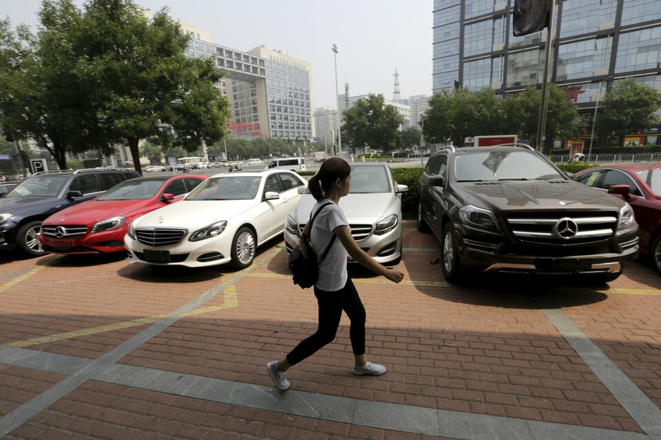 A woman walks past Mercedes-Benz cars displayed for sale outside a store in Beijing on Aug. 11. (Reuters Photo/Jason Lee)