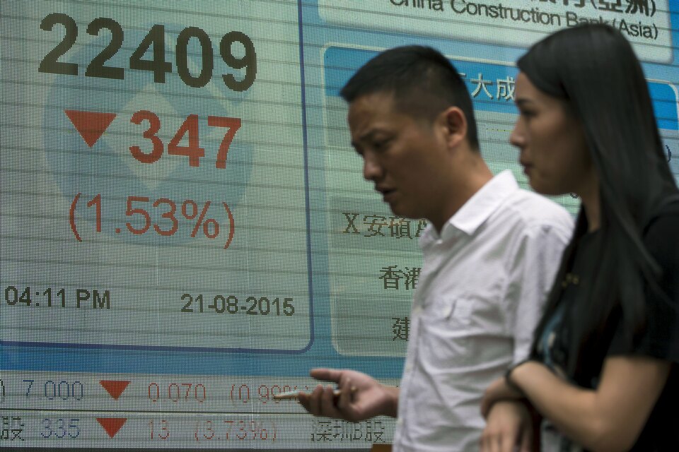 Passers-by walk in front of a panel displaying the closing Hang Seng Index, outside a bank in Hong Kong. (Reuters/Tyrone Siu)