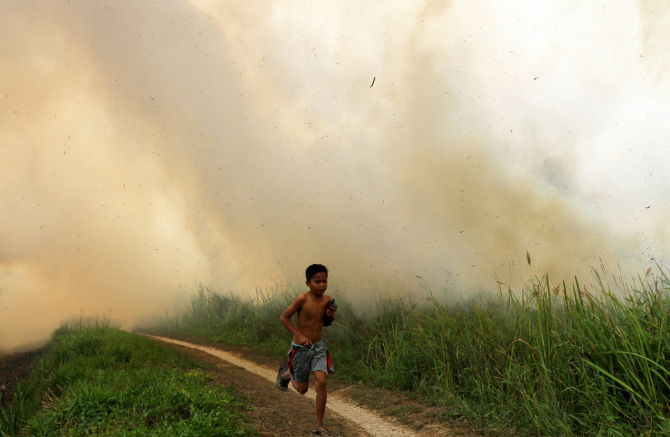 A child running away from smoky haze in  South Sumatra's Ogan Ilir district on Sunday. (Antara Photo/Nova Wahyudi) 