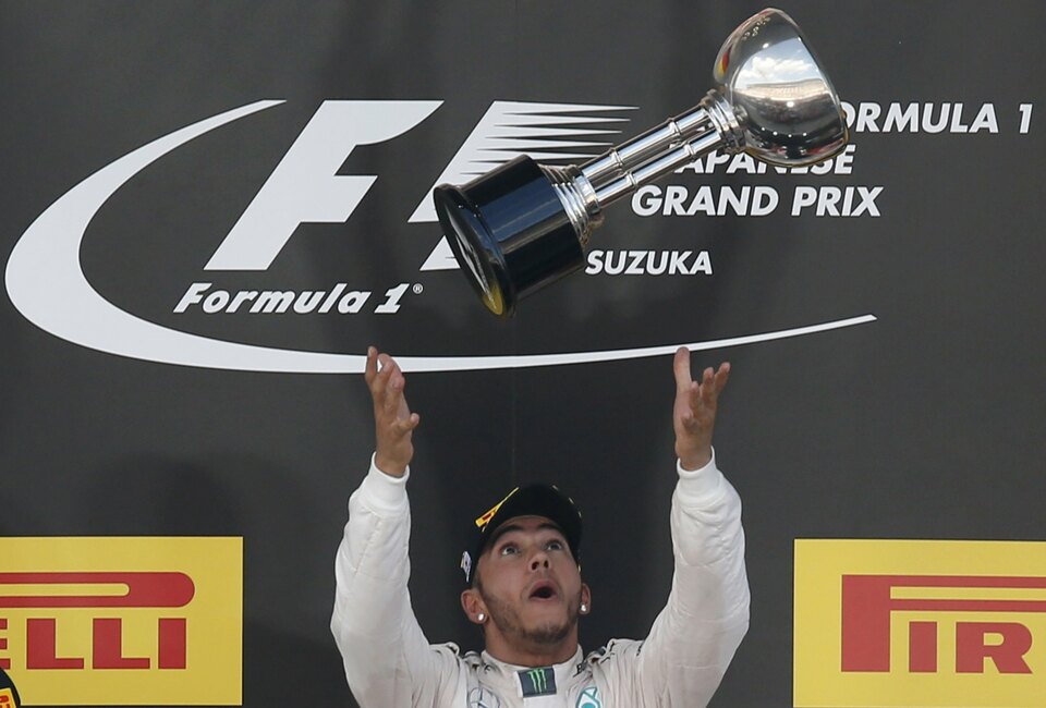 Mercedes Formula One driver Lewis Hamilton of Britain tosses his trophy into the air as he stands on the podium after winning the Japanese F1 Grand Prix at the Suzuka circuit in  Japan on Sunday. (Reuters Photo/Toru Hanai)