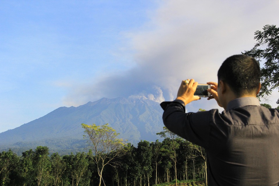 FILE - This undated photo shows a man take a photo of Mount Raung in Bejong Village, Banyuwangi Regency, East Java.(Antara Photo/ Budi Candra Setya)