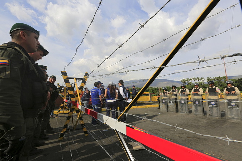 Colombian policemen stand guard in front of the border with Venezuelan policemen  August 27, 2015. Venezuela closed two border crossings and began deporting hundreds of Colombians, as part of measures the government says are designed to control smuggling and paramilitary activity. (Reuters/Jose Miguel Gomez)