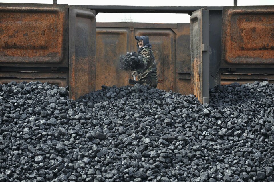 A worker unloads coal at a storage site along a railway station in Shenyang, Liaoning province, China in this April 13, 2010 file photo. (Reuters Photo/Sheng Li)