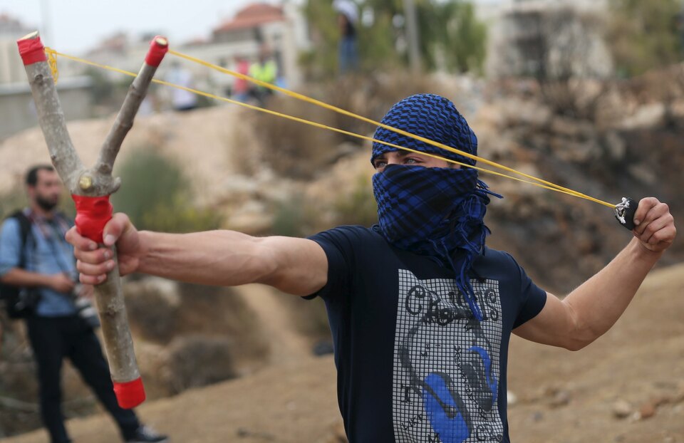 A Palestinian protester uses a sling shot to hurl stones at Israeli troops during clashes near the Jewish settlement of Bet El, near the West Bank city of Ramallah October 23, 2015. Palestinian factions called for mass rallies against Israel in the occupied West Bank and East Jerusalem in a "day of rage" on Friday, as world and regional powers pressed on with talks to try to end more than three weeks of bloodshed. (Reuters Photo / Mohamad Torokman)