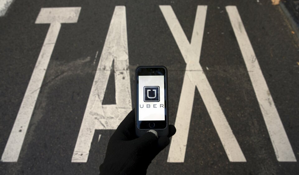 The logo of car-sharing service app Uber on a smartphone over a reserved lane for taxis in a street is seen in this file photo illustration taken in Madrid on December 10, 2014. (Reuters Photo/sergio Perez)