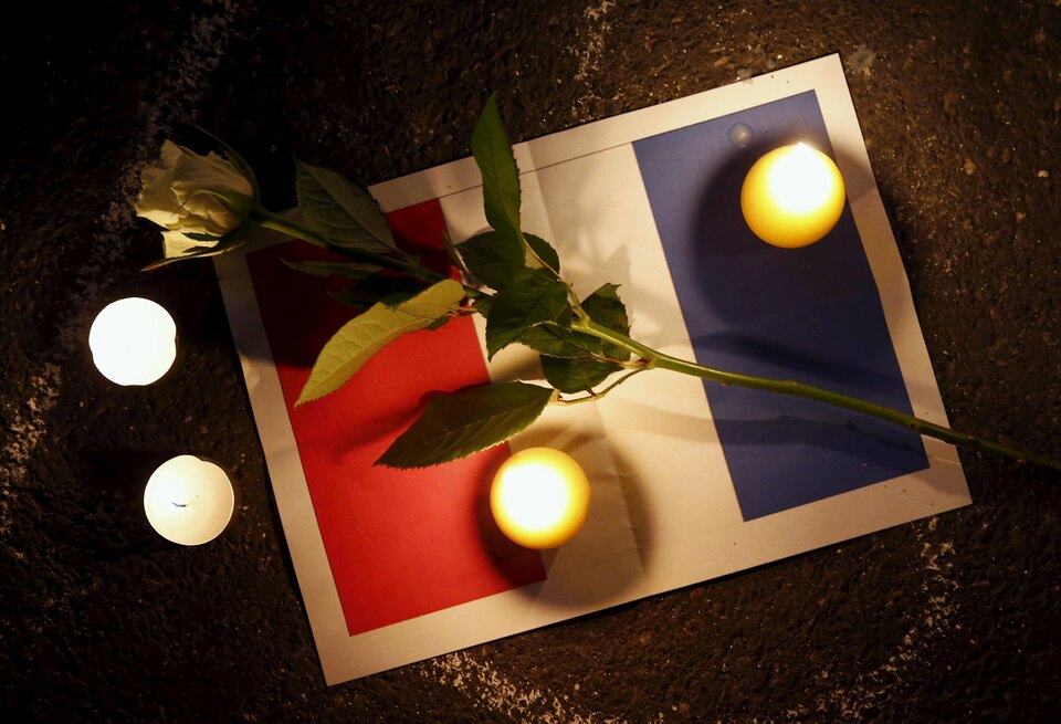 A rose is pictured on a sign depicting the flag of France next to candles during a ceremony for the victims the day after a series of deadly attacks in the French capital of Paris, in Lausanne, Switzerland, on Saturday. (Reuters Photo/Denis Balibouse)