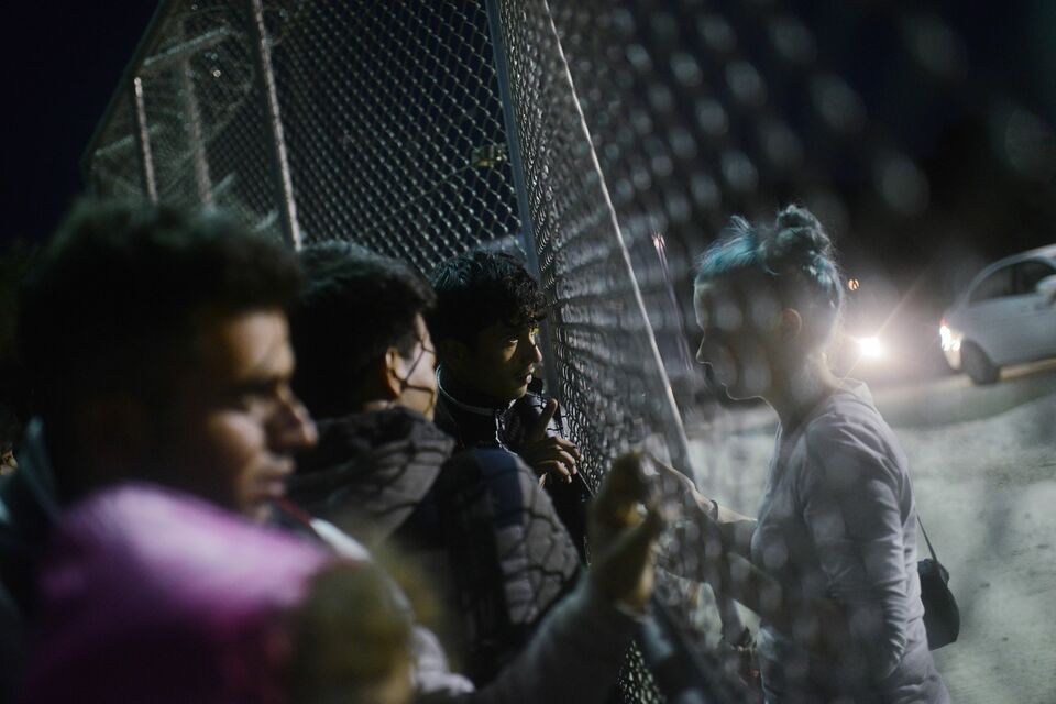 Refugees and migrants wait in front of a gate for registration in a camp on the Greek island of Lesbos after crossing the Aegean Sea from Turkey on November 16, 2015. European leaders tried to focus on joint action with Africa to tackle the migration crisis, as Slovenia became the latest EU member to act on its own by barricading its border. (AFP Photo/Bulent Kilic)