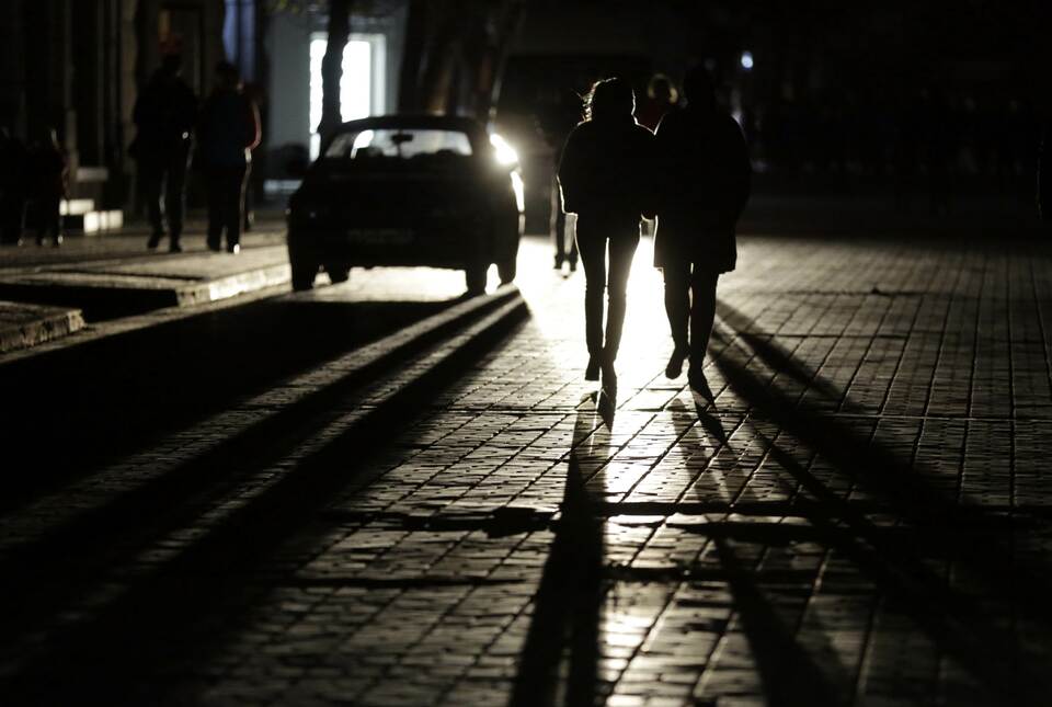 People walk along a street in central Simferopol on November 22, 2015. Crimea declared a state of emergency on Sunday after its main electricity lines from Ukraine were blown up, leaving the Russian-annexed peninsula in darkness after the second such attack in as many days. More than 1.6 million people are without power, water supplies to high-rise buildings have stopped and cable and mobile Internet is down. The electricity feed from Ukraine was cut at 00:25 am (2225 GMT), the Crimean branch of Russia's emergency situations ministry said in a statement. (AFP Photo/Max Vetrov)