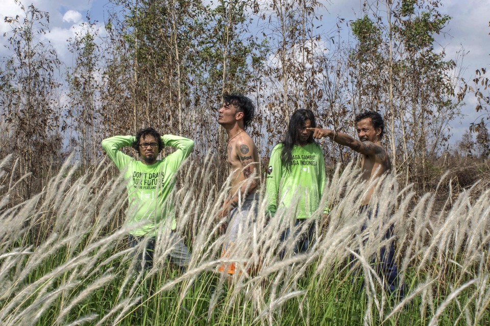 From left to right,  Tommy Maranu, Ahmad Afandi a.k.a Andi Babas,  Faried M Badjeber, Henry Limahelu  of the Indonesian rock band 'Boomerang’ pose for photographs during damming activity in Paduran village, Sebangau sub district ,Central Kalimantan province, Indonesia. Greenpeace and other NGOs are working with the Paduran community to re-wet peatlands and prevent future fires. Central Kalimantan was badly hit during the 2015 forest fires disaster.  Indonesia's peatlands cover just over 21 million hectares an area smaller than the UK. Yet this small area stores 57GtC, equivalent to more than 6 years of global emissions from fossil fuels. (Greenpeace Photo/Ardiles Rante)