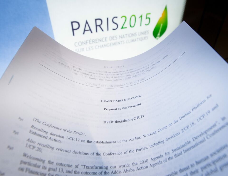 An illustration picture taken on December 10, 2015 in Paris shows a draft for the outcome of the COP21 United Nations conference on climate change next to the logo of the summit. (AFP Photo/Benoit Doppagne)