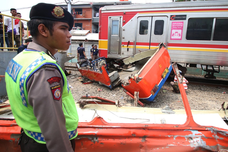 Eighteen people are dead and eight injured after a MetroMini bus was struck by a train in West Jakarta on Sunday morning, the second such incident in just over a week. (Antara Photo/Rivan Awal Lingga)