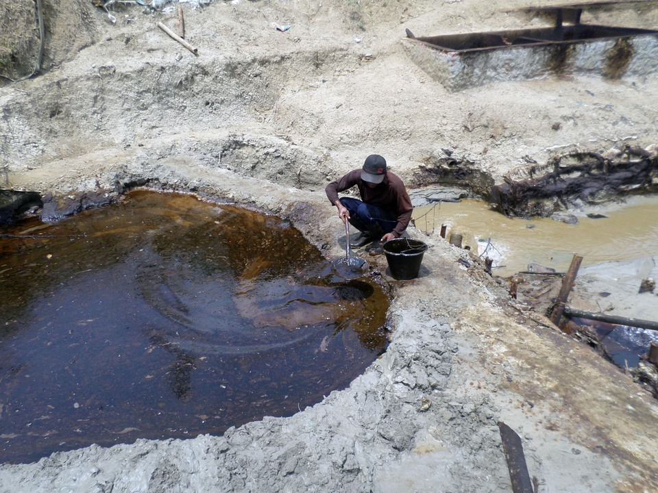 A miner scoops up crude oil at a traditional oil-drilling operation in Bojonegoro, (Photo: ANTARA/Aguk Sudarmojo)