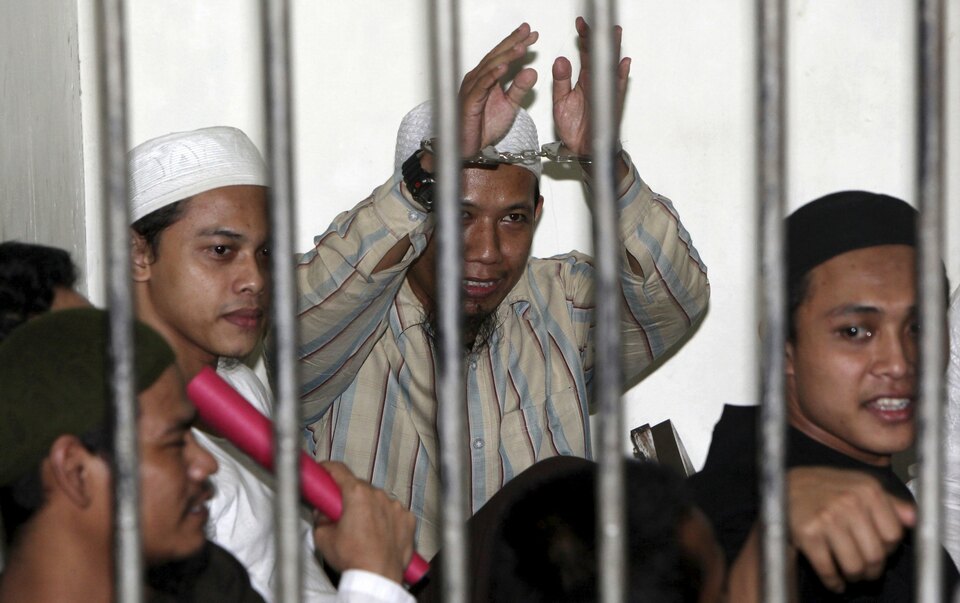 Radical Muslim cleric Aman Abdurrahman (center), also known as Oman Rochman, raises his hands in a holding cell as he waits with other militants for their trial in Jakarta, in this Aug. 26, 2010 file photo. (Reuters Photo/Dadang Tri)