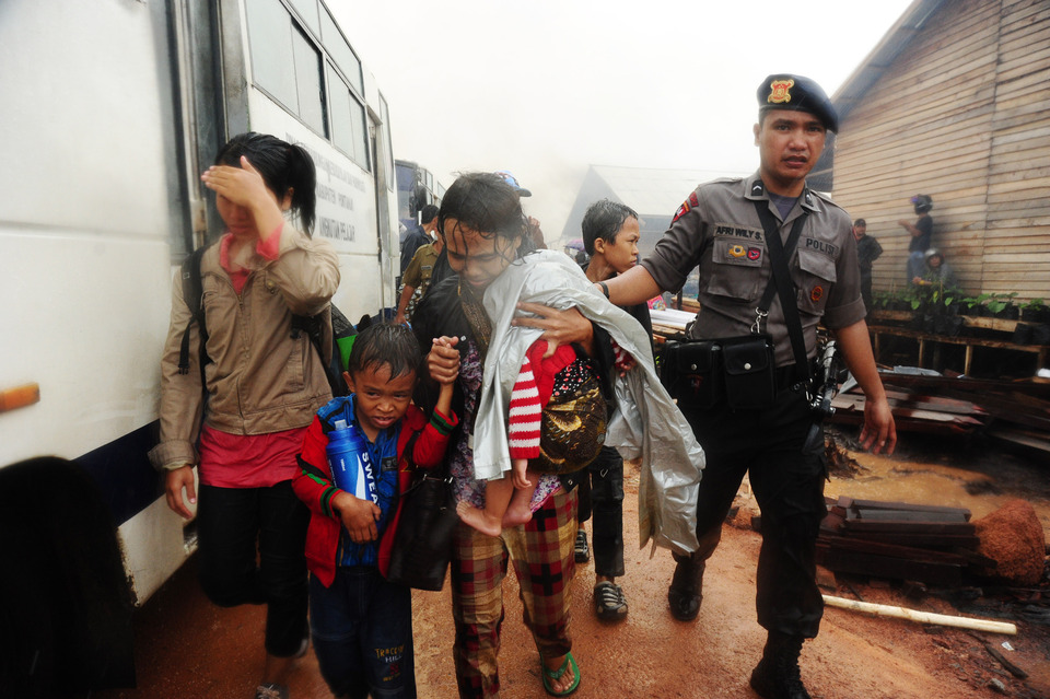 A police officer escorts former members of the Fajar Nusantara Movement (Gafatar) from their village in West Kalimantan on Tuesday. (Antara Photo/Jessica Helena Wuysang)