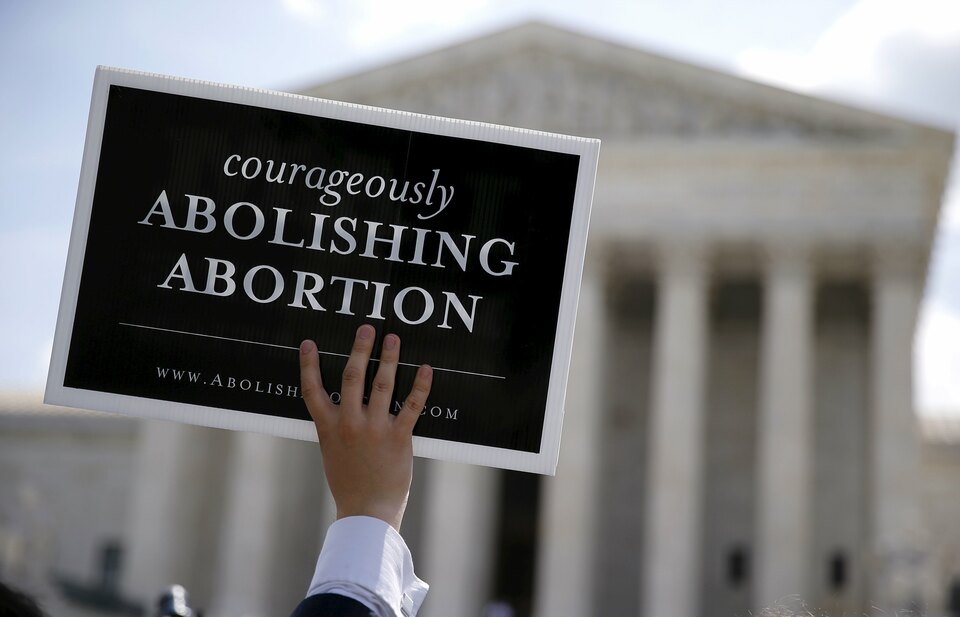 An anti-abortion protester with a group celebrating the US Supreme Court's ruling striking down a Massachusetts law that mandated a protective buffer zone around abortion clinics, holds up a sign outside the Court in Washington, in this June 26, 2014 file photo. When the US Supreme Court on March 2, 2016 hears a major case on abortion for the first time in nearly a decade, the regulations at issue will not involve fetuses or the mother, but rather standards for doctors and facilities where the procedure is performed. (Reuters Photo/Jim Bourg)