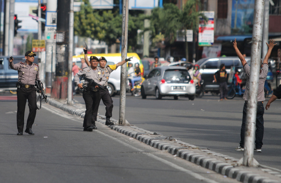 Police officers order a pedestrian on Sunday (31/1) to back away from the scene of a fatal clash between two youth groups in Medan, North Sumatra.  Two people were reportedly killed and at least four others injured when violence broke out between Pemuda Pancasila (PP) and the Working Youth Alliance (IPK) on Saturday. (Antara Photo/Irsan Mulyadi).