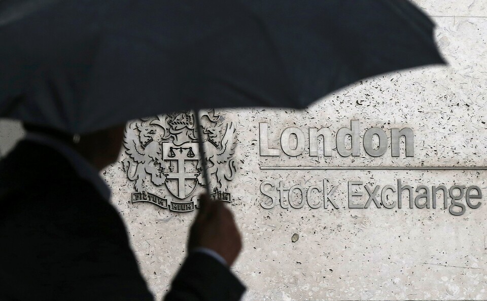 A man shelters under an umbrella as he walks past the London Stock Exchange in London, Britain, Aug. 24, 2015. Deutsche Boerse and the London Stock Exchange are taking a fresh run at a merger that would create a large European exchange operator potentially capable of facing down strong competition from the United States and Asia.The LSE said in a statement it was holding detailed discussions on an all-share merger under a new holding company that would give Deutsche Boerse shareholders a 54.4 percent stake and LSE shareholders 45.6 percent. (Reuters Photo/Suzanne Plunkett)