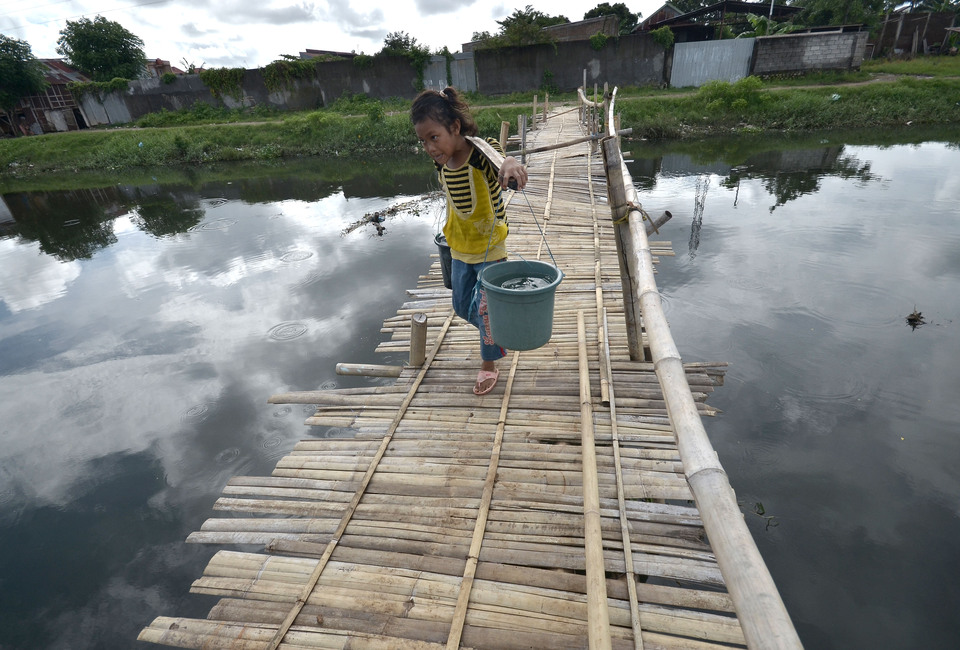 Eight-year-old Isma carries water taken from a well located near her home in Makassar, South Sulawesi, on March 1. Residents in the slum area either have to buy tap water, or ask neighbors for groundwater to meet their daily requirements. (Antara Photo/Dewi Fajriani)