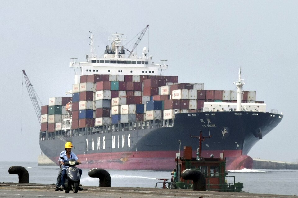 People ride a motorcycle while a container ship passes by at Keelung port in northern Taiwan in this July 20, 2010 file photo.    (Reuters Photo/Pichi Chuang)