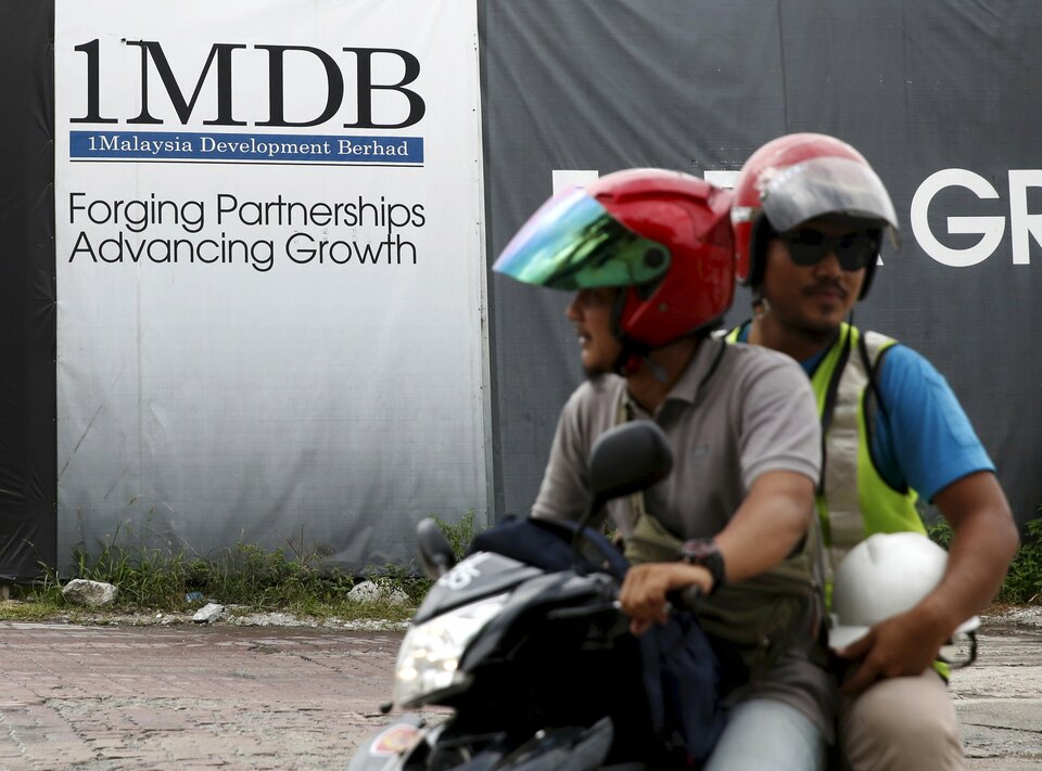 Motorcyclists pass a 1Malaysia Development Berhad (1MDB) billboard at the Tun Razak Exchange development in Kuala Lumpur. (Reuters Photo/Olivia Harris)