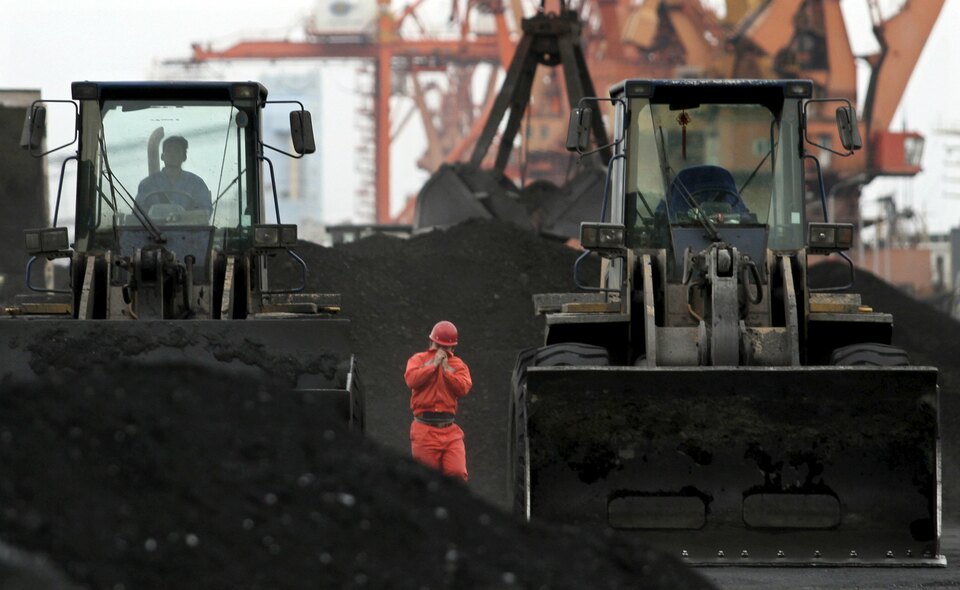 An employee walks between front-end loaders, which are used to move coal imported from North Korea, at Dandong port in the Chinese border city of Dandong, Liaoning province. (Reuters Photo)