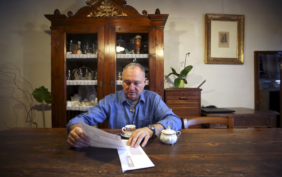 Domenico Bertini reads a letter from Banca Popolare di Vicenza in his house in Lonigo, near Vicenza, Italy. (Reuters Photo/Stefano Rellandini)