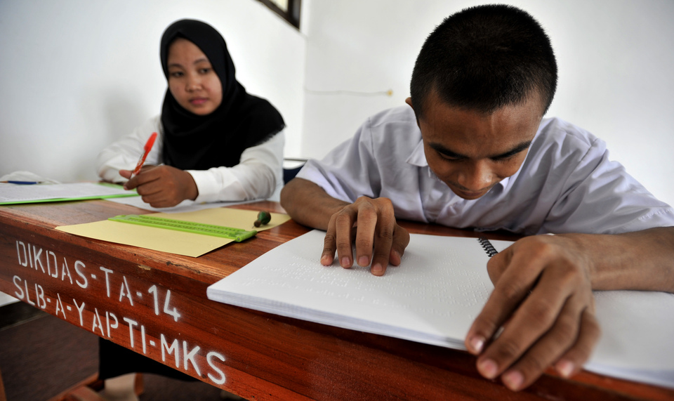 A visually impaired student, right, reads braille script while seated beside an assistant during the national exams in Makassar, South Sulawesi, in this April 4, 2016 file photo. Five companies have launched the Indonesia Business and Disability Network in Jakarta on Friday (15/12), aimed at promoting diversity and inclusivity in the workplace. (Antara Photo/Yusran Uccang)