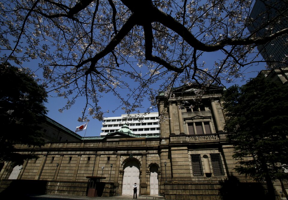 A security officer stands guard near half-blooming cherry blossoms, outside the Bank of Japan headquarters in Tokyo, Japan. (Reuters Photo/Yuya Shino)