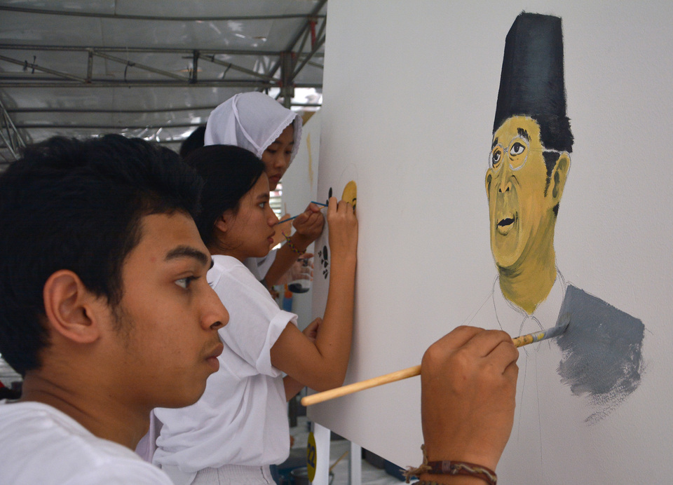 A high-school student draws a mural of Ki Hajar Dewantara, the country's national education pioneer, to celebrate National Education Day in Jakarta on Monday (02/05). (Antara Photo/Aprillo Akbar)