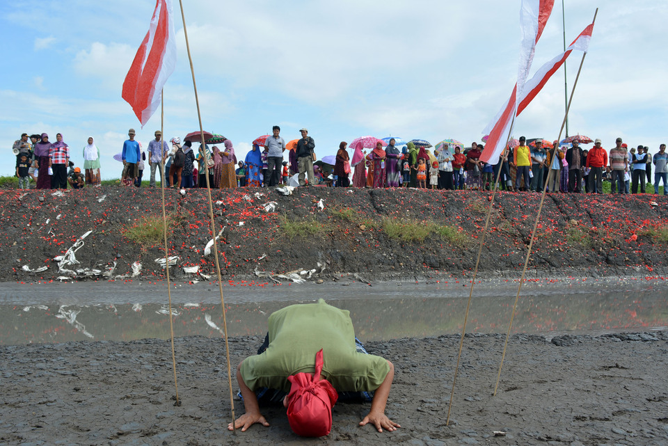 A resident bowing down after spreading flowers at the mud embankment in Porong, Sidoarjo, East Java, on Monday (30/5). The action is as a symbol of concern and commemoration of the 10 years since the Lapindo mudflow began. (Antara Photo/Umarul Faruq)