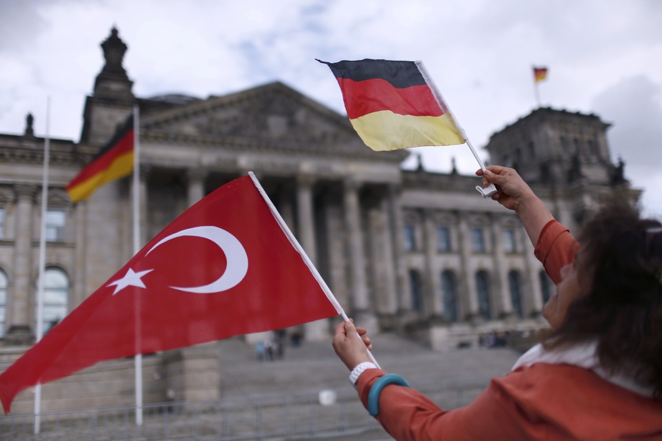 A demonstrator holds Turkish and German flags in front of the Reichstag, the seat of the lower house of parliament Bundestag in Berlin, Germany, June 1, 2016, as she protests against a disputed vote in Germany's parliament on Thursday, on a resolution that labels the killings of up to 1.5 million Armenians by Ottoman forces as genocide. (Reuters Photo/Hannibal Hanschke)