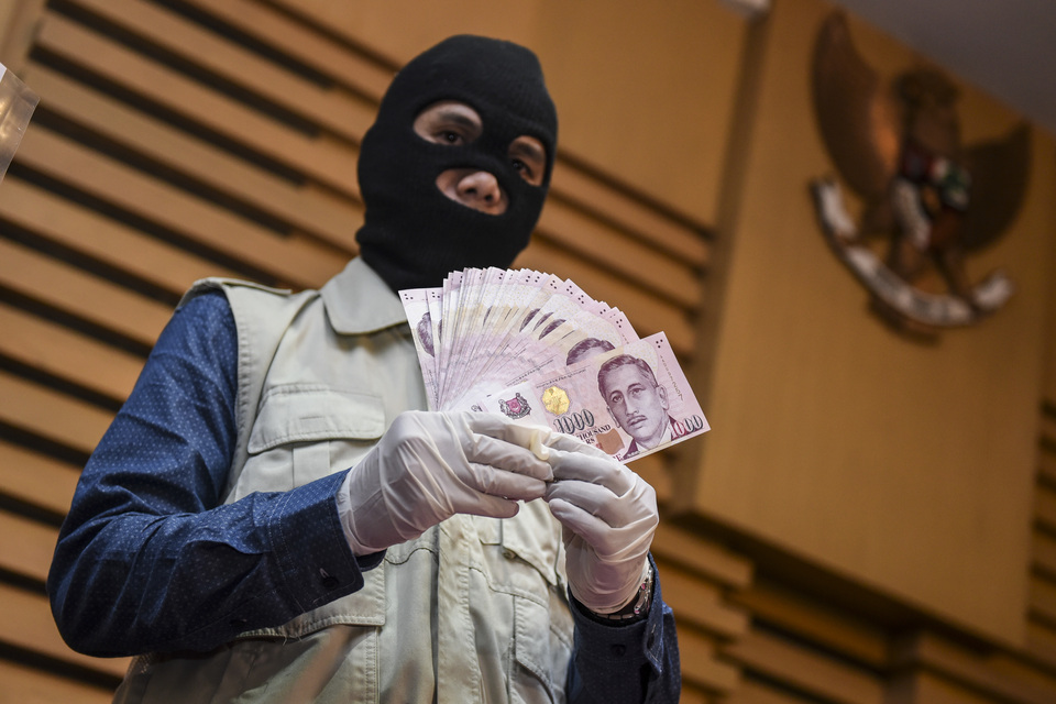 A KPK officer shows S$40,000 ($29,600) in cash seized from a corruption suspect. (Antara Photo/Hafidz Mubarak A.)