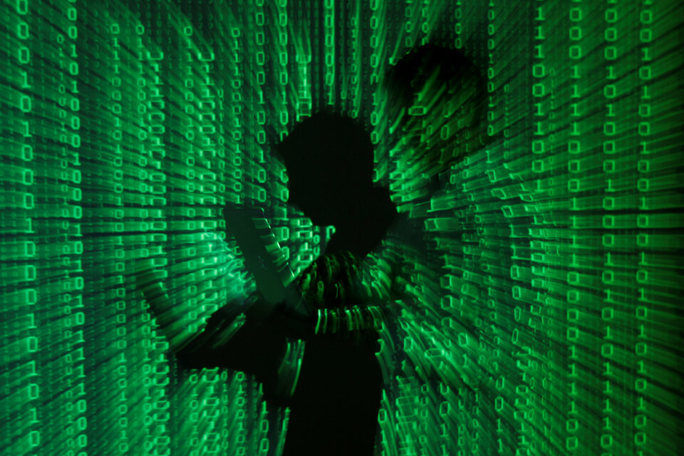 An illustration picture shows a projection of binary code on a man holding a laptop computer.  (Reuters Photo/Kacper Pempel)