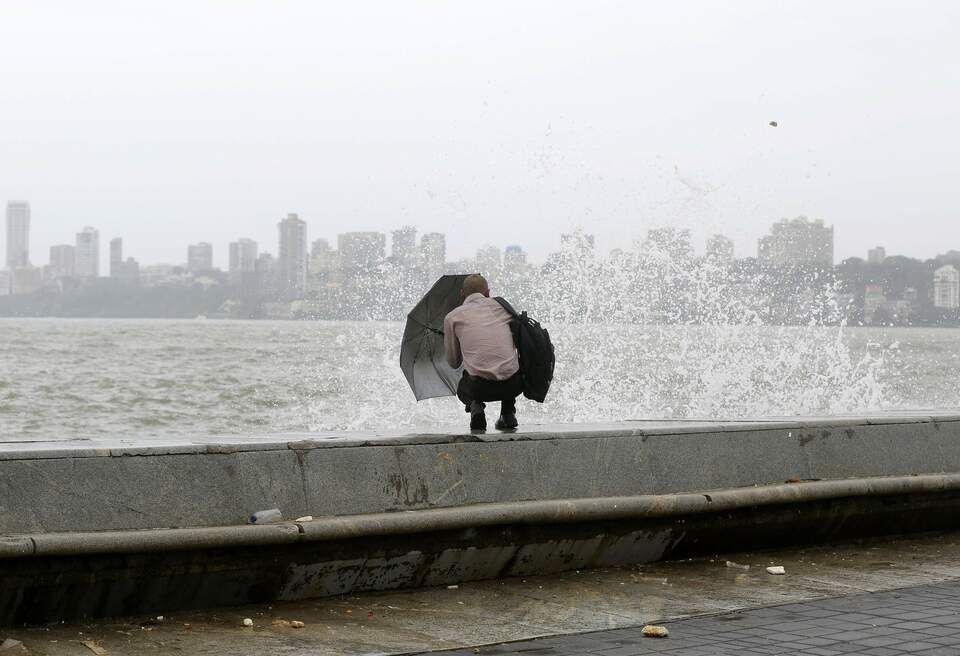A man uses his umbrella to shield himself from a wave during high tide at the sea front in Mumbai, India, July 5, 2016. (Reuters Photo/Shailesh Andrade)
