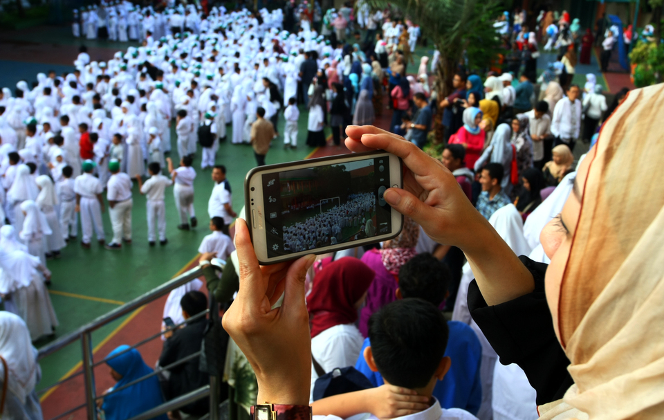 A woman takes a photo of students at an Islamic elementary school, or madrasah, in Ciputat, South Tangerang, on Monday (18/07), the first day of the new school year. (Antara Photo/Muhammad Iqbal)